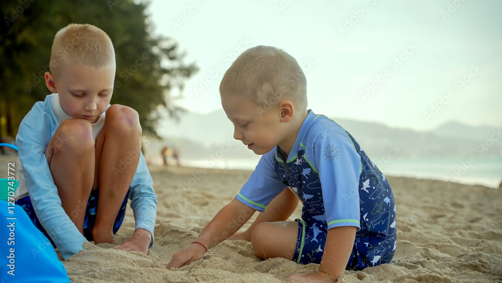 Two children are enjoying a sunny afternoon on the beach, building sandcastles and digging in the warm sand. The beautiful scenery includes distant mountains and gentle waves. Two children are enjoying a sunny afternoon on the beach, building sandcastles and digging in the warm sand. The beautiful scenery includes distant mountains and gentle waves.