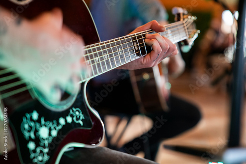 Guitarrista tocando la guitarra en un concierto acústico con la mano enfocada en los trastes photo