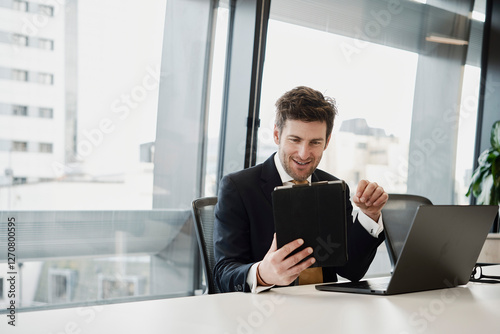 Businessman multitasking with laptop and tablet in modern office