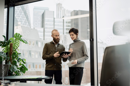 Businessman discussing with colleague through tablet PC in office