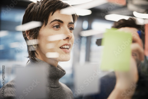 Short haired businesswoman writing on glass wall with felt tip pen photo