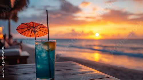 Refreshing cocktail with umbrella at sunset on tropical beach with soft waves
