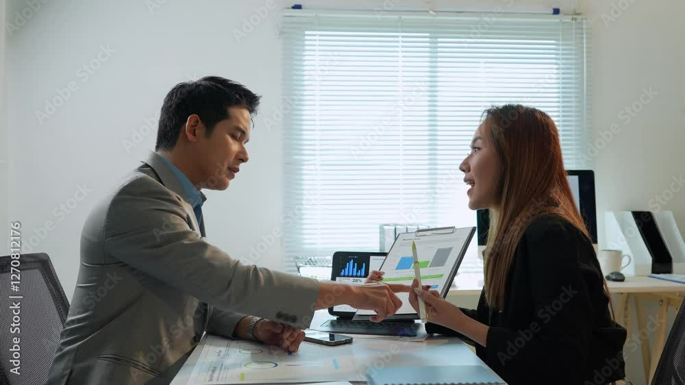Business professionals analyzing market data while collaborating at desk, discussing charts and performance in modern corporate office setting Business professionals analyzing market data while collaborating at desk, discussing charts and performance in modern corporate office setting
