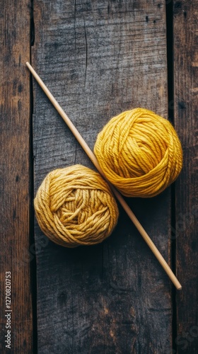 Yarn balls and knitting needles arranged on a rustic wooden surface for creat...