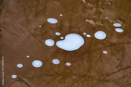 Bąble powietrza uwięzione pod lodem tworzą nieregularne jasne plamy photo