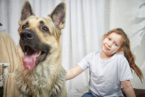 Happy girl sits with her large dog in a cozy indoor setting during the afternoon photo