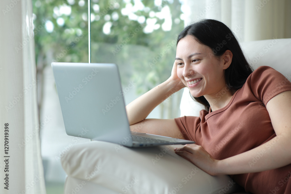 Happy asian woman using laptop sitting at home Happy asian woman using laptop sitting at home
