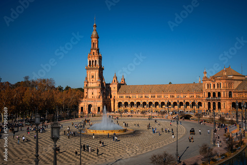 Crowds of tourists walk and explore the iconic Plaza de España historic square in Seville Spain on a bright autumn day