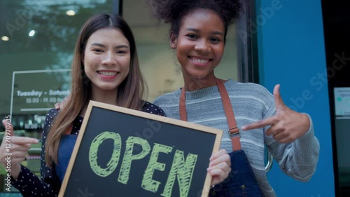 Two woman owner hold open sign at refill shop.