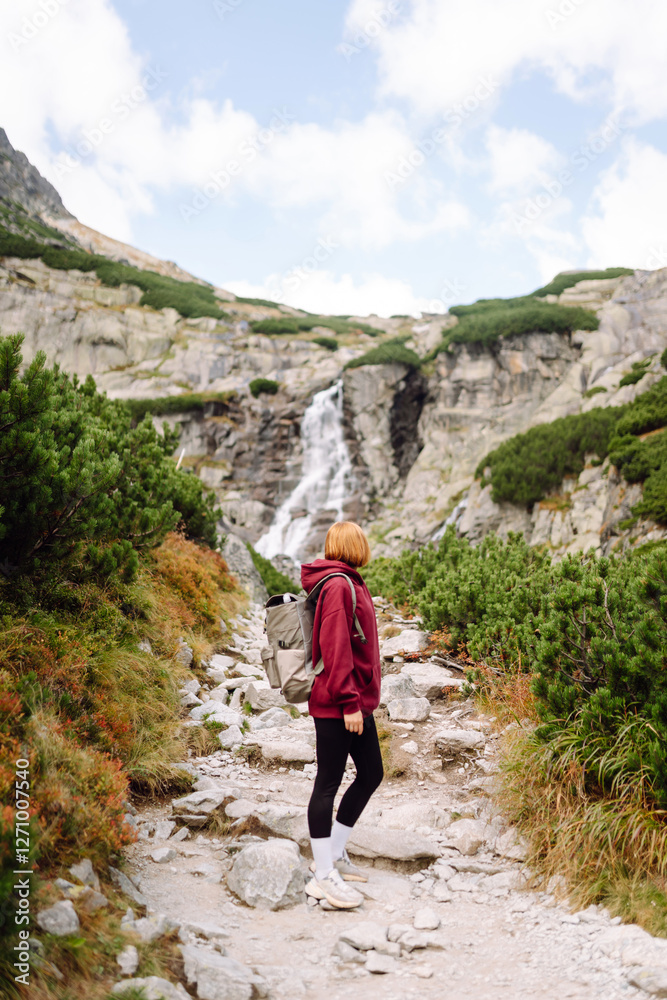 Naklejka premium Woman traveler walking on mountains cliff in summer sunny day under sun light. Adventure active. Tourism