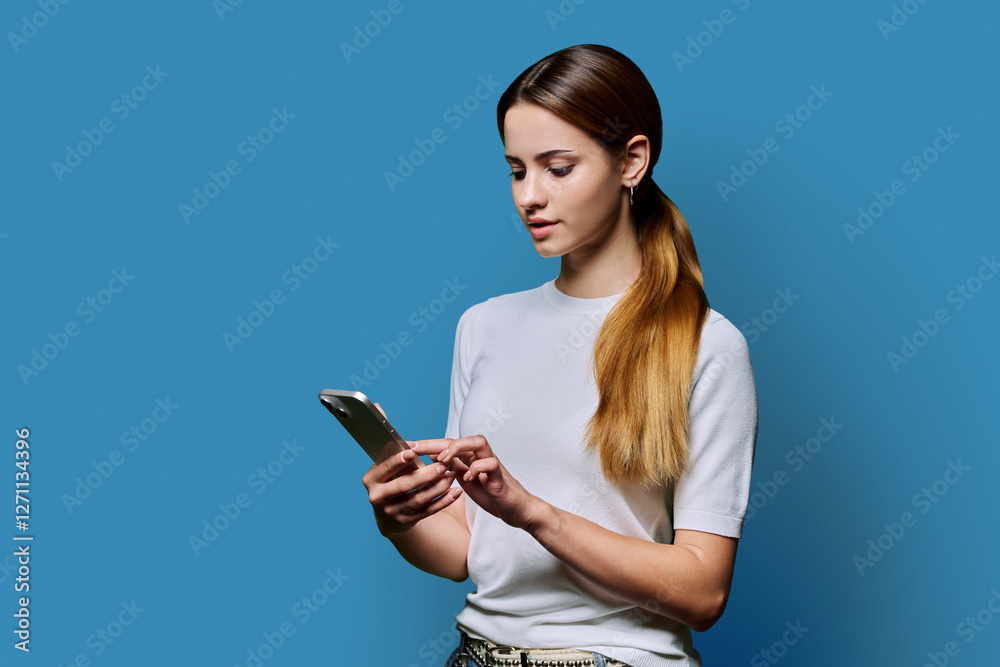 Young beautiful woman using smartphone on blue studio background Young beautiful woman using smartphone on blue studio background