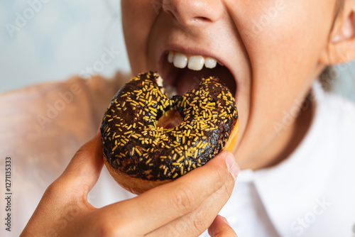 A sweet doughnut in hand. Little girl eating cupcake messily. The girl is eating sweet pastries. photo