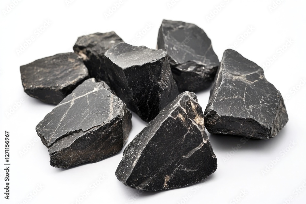 A pile of black rocks arranged on a white surface, great for use in still life compositions or as a design element A pile of black rocks arranged on a white surface, great for use in still life compositions or as a design element