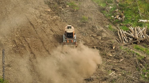 A mulcher shred organic material, leaves, branches, grass, or other plant debris, into smaller pieces. Construction of a road through the forest. Cutting and clearing of forest for road construction.