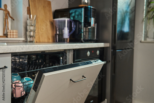 Obraz na płótnie Partially open dishwasher filled with clean ceramic bowls and cups in modern kitchen. Energy-efficient home appliance for convenient dish cleaning w salonie