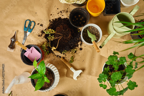 Close-up of gardening tools, potted plants and soil scattered on floor during repotting plant process. Concept of home gardening, and spring houseplant care photo