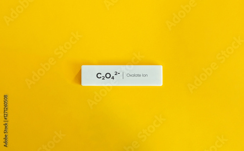 The chemical formula for the oxalate ion, C₂O₄²⁻. Text on Block Letter Tile on Yellow Background. Minimal Aesthetic.