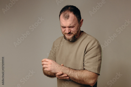 A man holds his wrist in pain. The hand tightly clasps the affected area, emphasizing the soreness and need for support. Pain and suffering in the wrist interfere with professional activities.