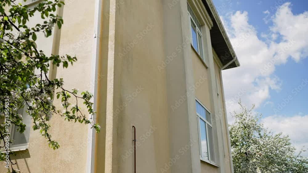 The process of cleaning the exterior of a house using water and solution. A man using a pressure washer on the siding of a house. Cleaning and maintenance concept.