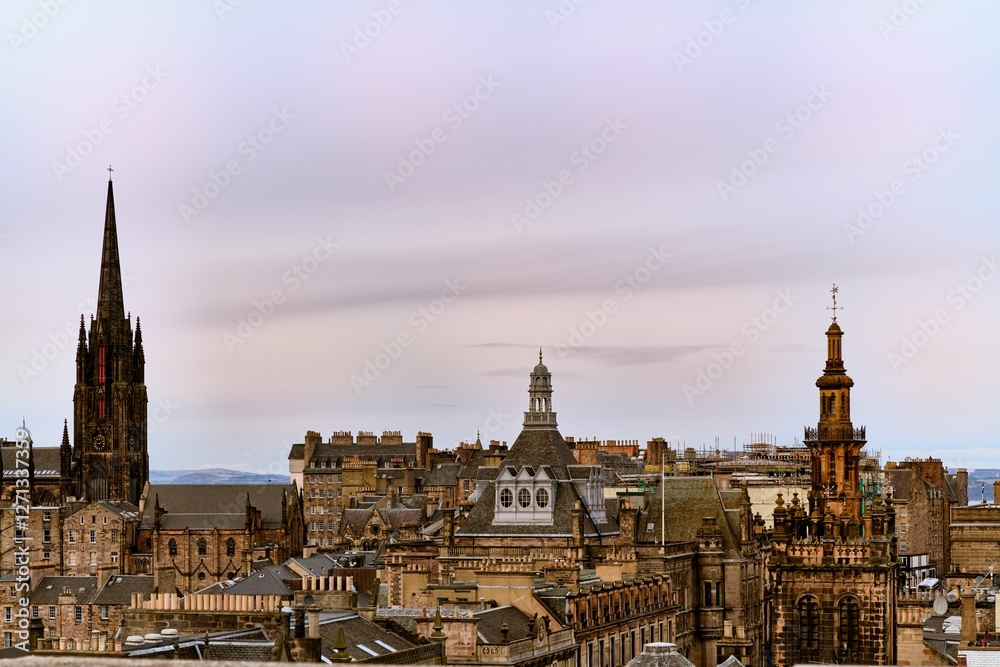 Fototapeta premium View of Edinburgh's historic skyline featuring iconic spires and architecture under a pastel sky.