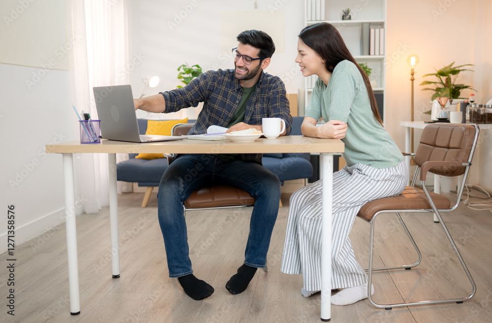 Portrait of a young freelancer smiling while working online via laptop at home with his girlfriend Portrait of a young freelancer smiling while working online via laptop at home with his girlfriend