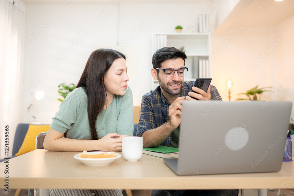 Portrait of a young freelancer smiling while working online via laptop at home with his girlfriend Portrait of a young freelancer smiling while working online via laptop at home with his girlfriend