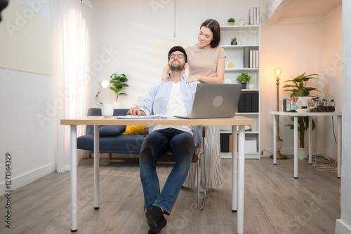 Portrait of a young freelancer smiling while working online via laptop at home with his girlfriend