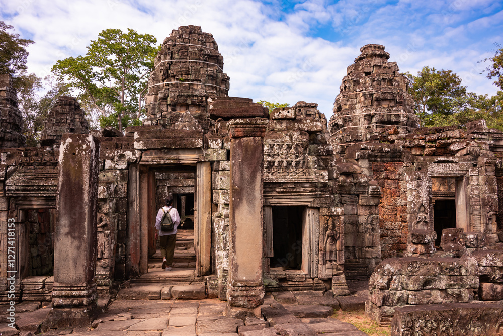 Naklejka premium Tourist entering Angkor ancient temple ruins in Cambodia