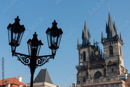 A striking view of Prague's iconic Gothic architecture, featuring the Church of Our Lady before Týn with its towering spires and an ornate vintage street lamp in the foreground. photo