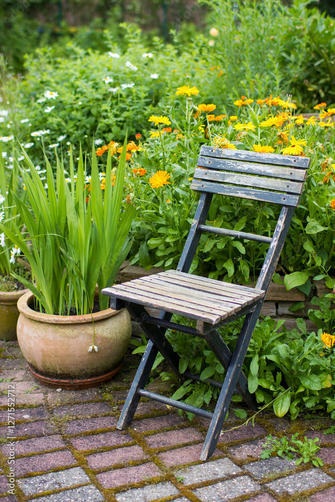 wild garden - herb spiral in the garden with fresh herbs and flowers and old chair