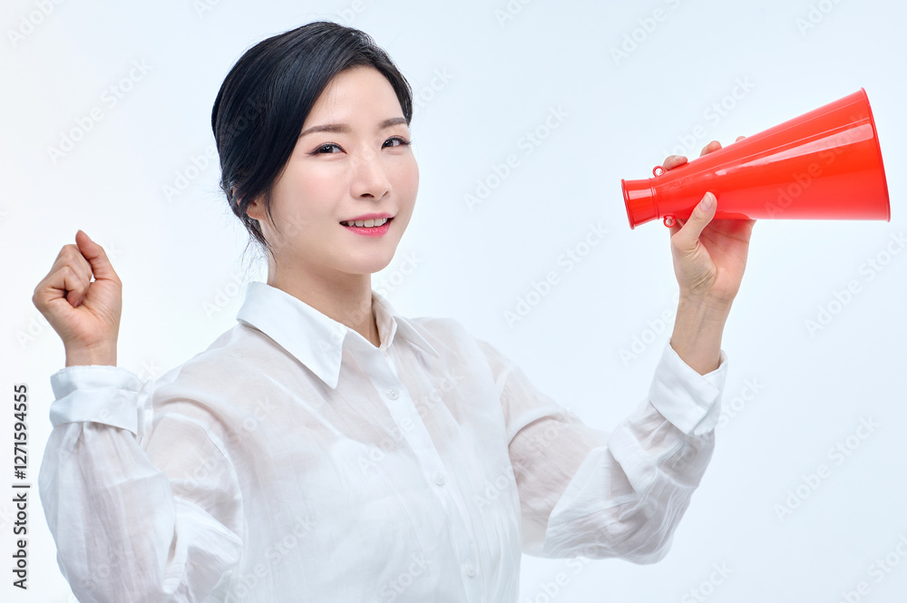 A businesswoman in a formal suit is posing while holding a red megaphone.
A businesswoman in a formal suit is posing while holding a red megaphone.