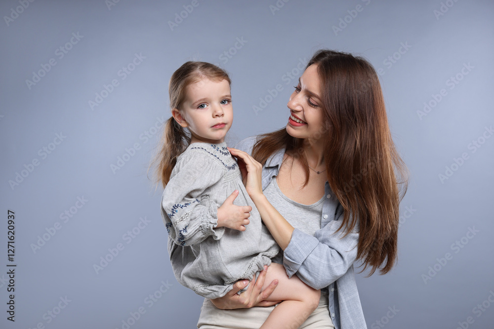 Happy mother with her cute little daughter on grey background Happy mother with her cute little daughter on grey background