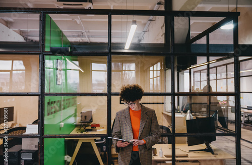 Fototapet Young woman standing while working with tablet in modern office