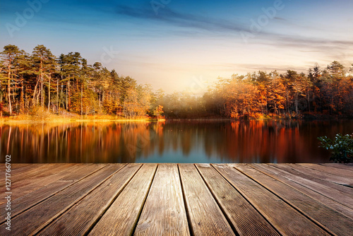 Wooden floor or plank in tranquil orange autumn forest trees, lake fallen leaves background. Royalty high-quality free best stock of empty wooden planks for product display. Peaceful landscape nature