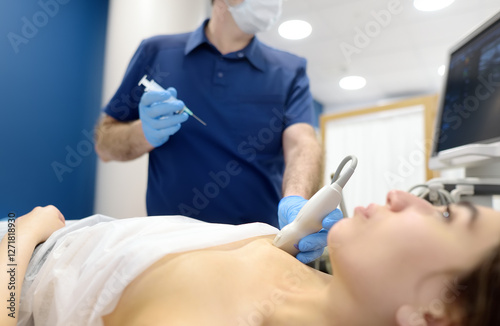 Skillful oncologist puncture of mammary glands of young patient under review ultrasound for diagnosis of breast cancer.