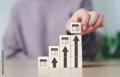 Franchise business growth and expansion concept. Hand stacking wooden blocks with store and arrow icons, franchise business growth, expansion, success entrepreneurship, market development, online shop