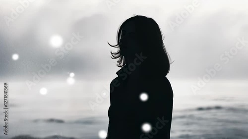 Woman silhouetted against stormy ocean, windswept hair, contemplative mood