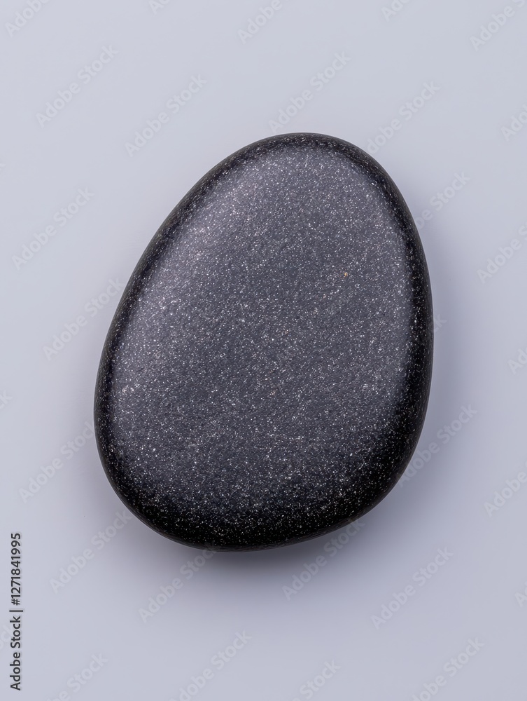 A smooth black stone with a shiny surface against a light background. A smooth black stone with a shiny surface against a light background.