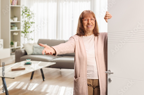 Excited mature woman behind a door gesturing welcome