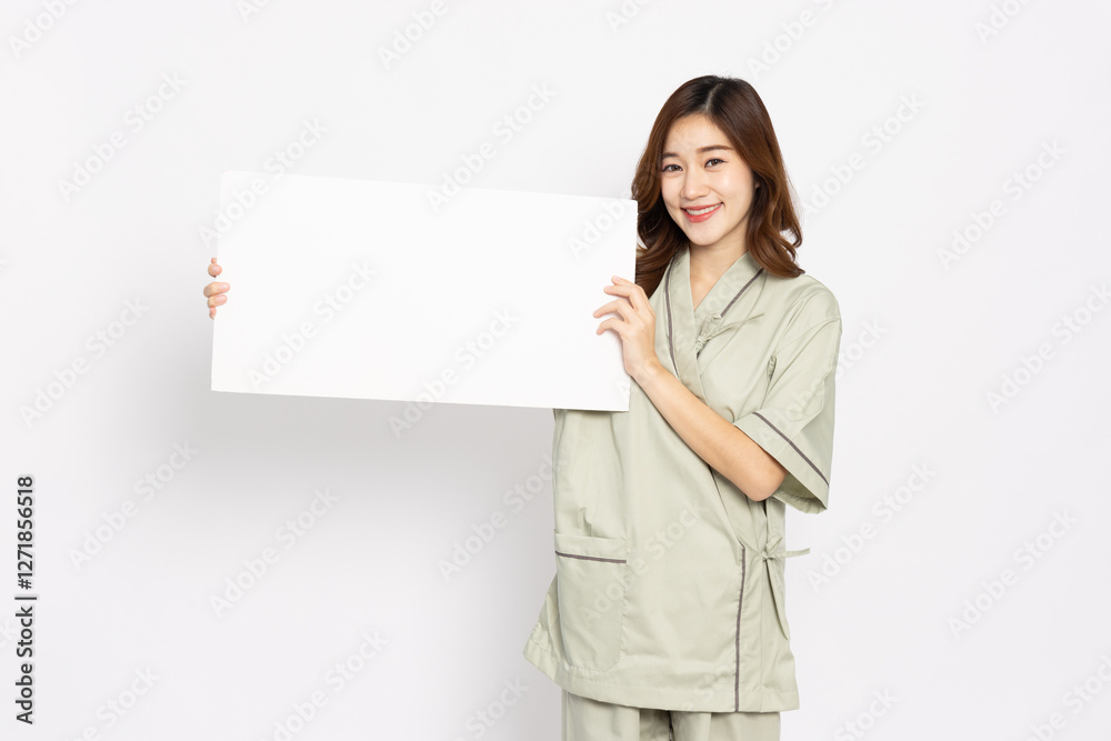 Asian woman in patient outfit smiling and showing blank white billboard advertising isolated on white background Asian woman in patient outfit smiling and showing blank white billboard advertising isolated on white background