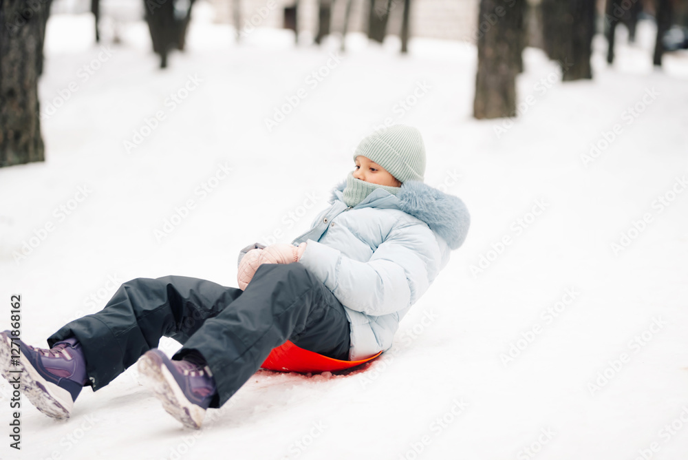 Girl sliding down snowy hill enjoying winter holidays Girl sliding down snowy hill enjoying winter holidays