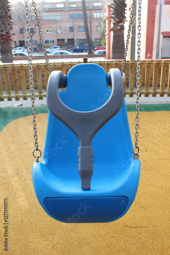 Inclusive playground for children with functional diversity and physical disabilities. Blue swing with seat and safety lock for kids in wheelchairs and disabled people.