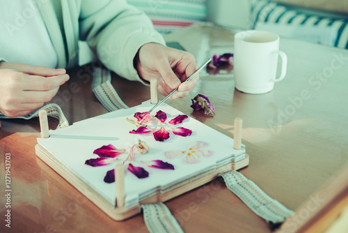 pressing flowers process, ypung hand arranging plants for drying in flower press kit, lovely hobby day with cup of coffee, art of oshibama photo