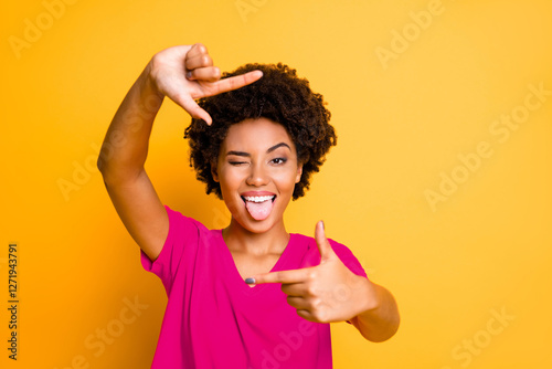 Photo of charming cut flirty black girlfriend showing you cadre frame pretending to be photographing tongue out blinking isolated with yellow vivid color background
