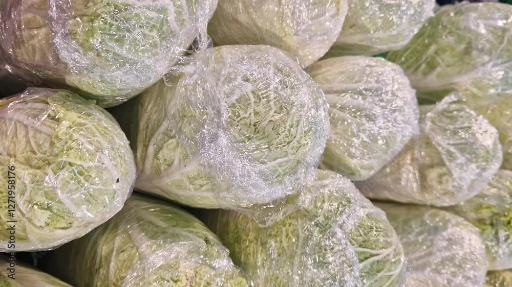 Chinese cabbage wrapped in plastic. Cabbage for sale in a supermarket or vegetable market. Vegetables. Products at the market. Close-up of Chinese cabbage on a shelf in a store Chinese cabbage wrapped in plastic. Cabbage for sale in a supermarket or vegetable market. Vegetables. Products at the market. Close-up of Chinese cabbage on a shelf in a store