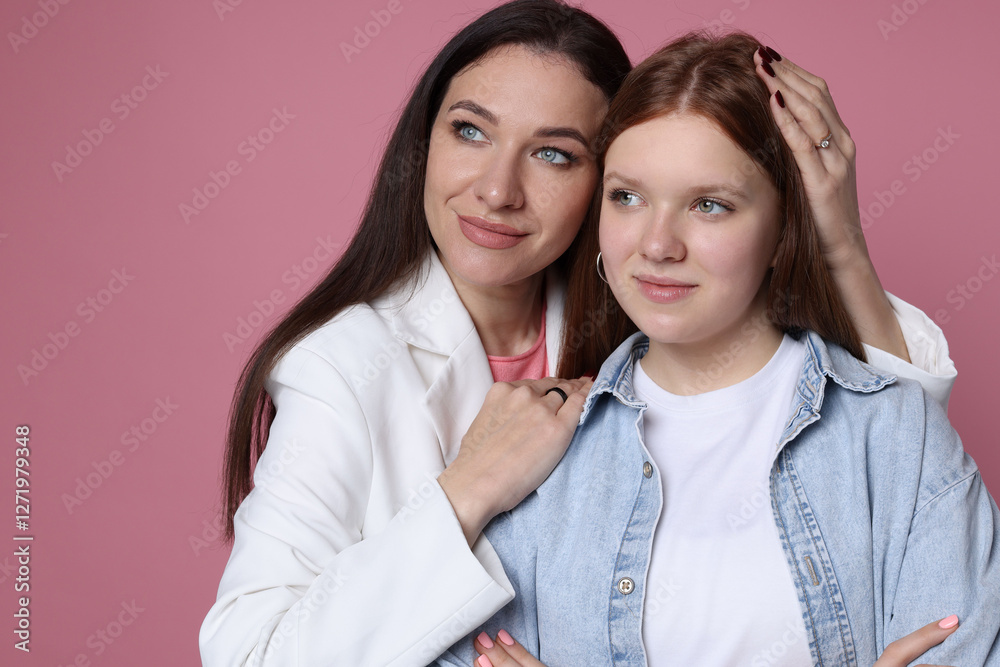 Family portrait of beautiful mother with teenage daughter on pink background Family portrait of beautiful mother with teenage daughter on pink background