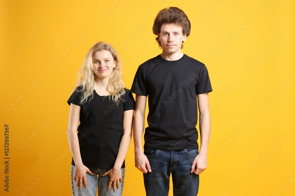 Young woman and man wearing blank black t-shirts on orange background. Mockup for design Young woman and man wearing blank black t-shirts on orange background. Mockup for design