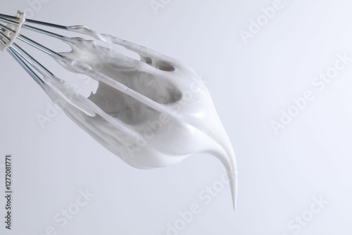 фотографія Whisk with whipped cream on white background, closeup
