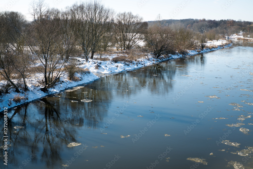 A river in winter and pieces of ice flowing through it, floes.