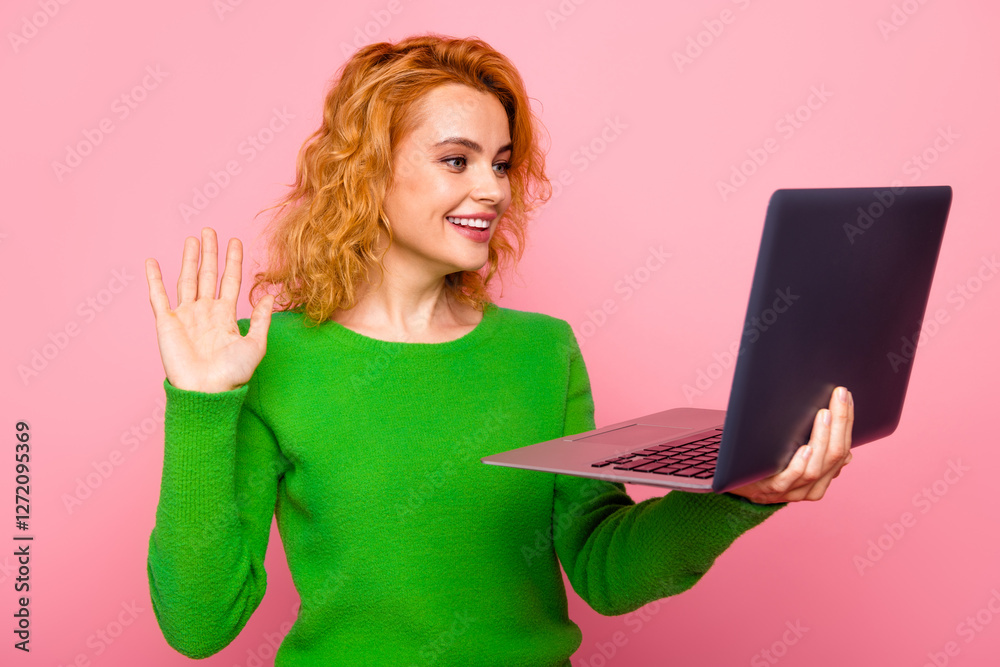 Cheerful Young Woman Wearing Green Sweater Holding Laptop and Waving on a Pink Background Cheerful Young Woman Wearing Green Sweater Holding Laptop and Waving on a Pink Background